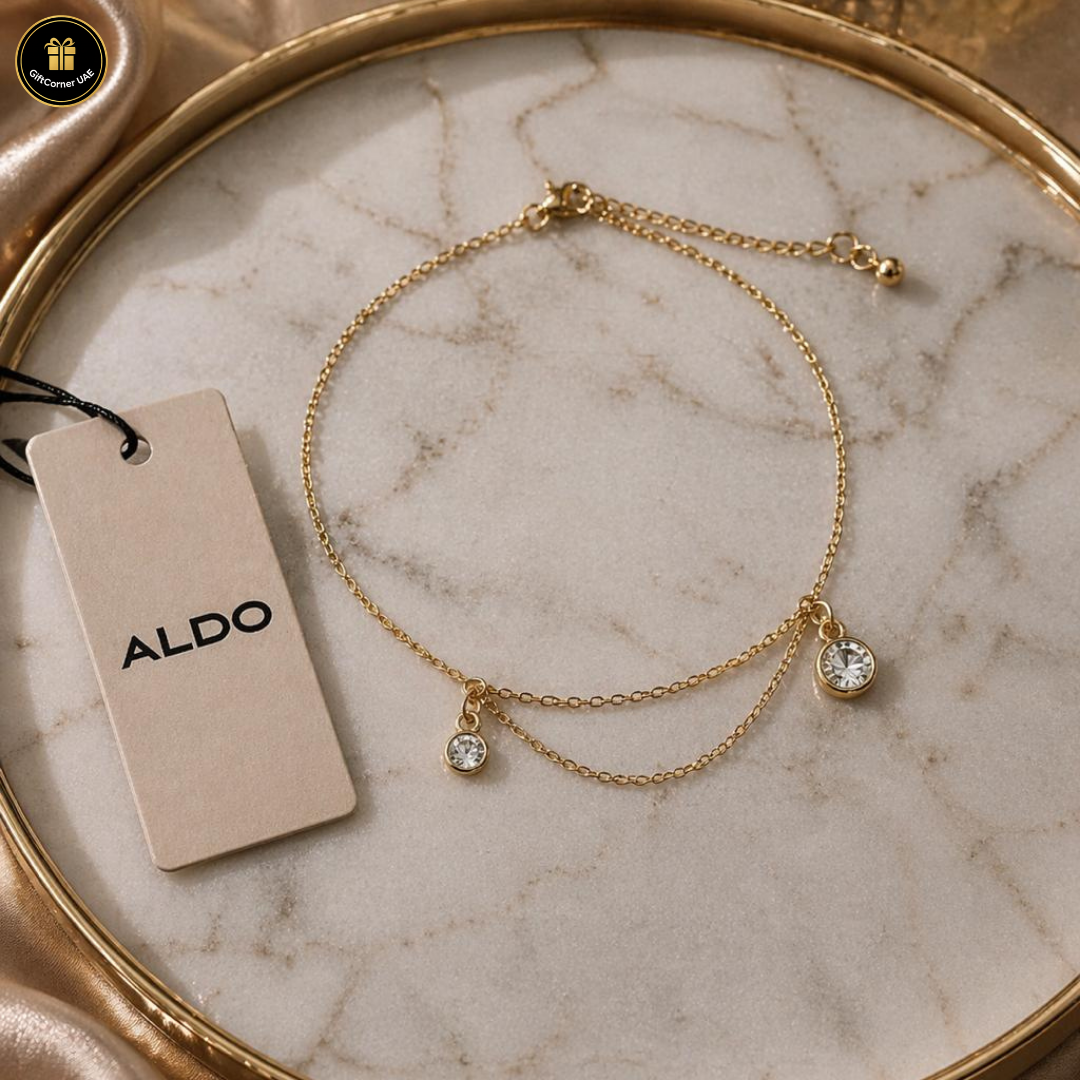 Gold bracelet with diamond charms on a marble surface with an Aldo tag.
