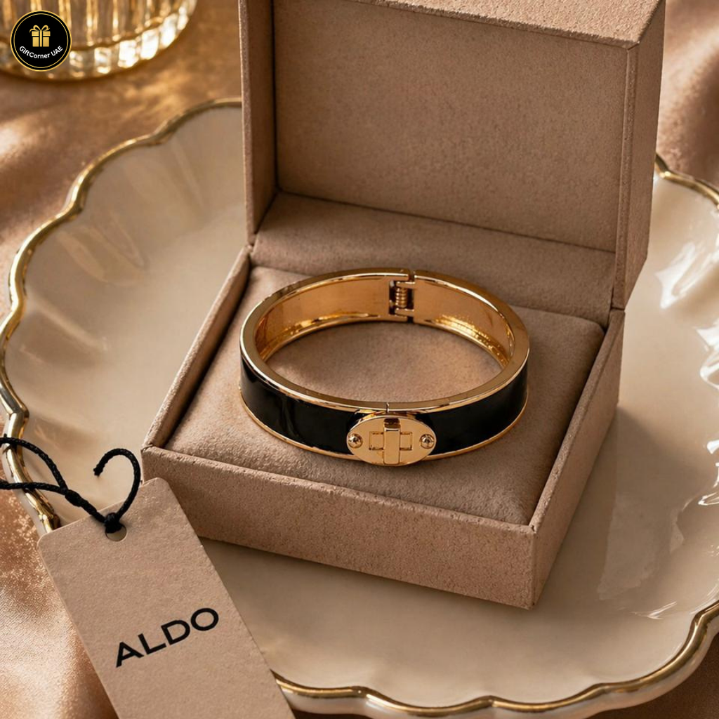 Gold and black bracelet in a box with an Aldo tag on a decorative surface