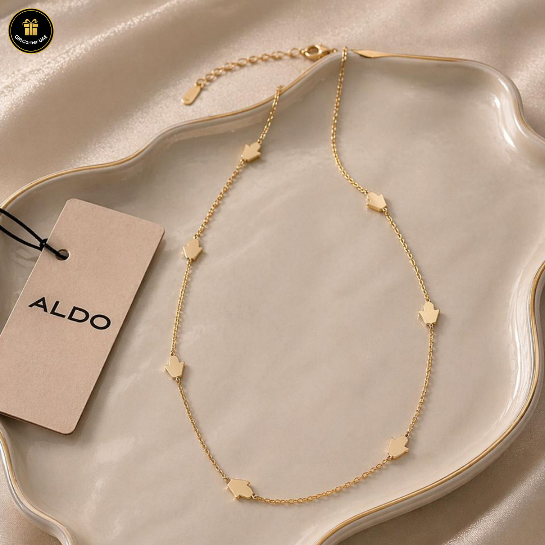 Gold necklace with star-shaped pendants on a beige dish, accompanied by an Aldo tag.