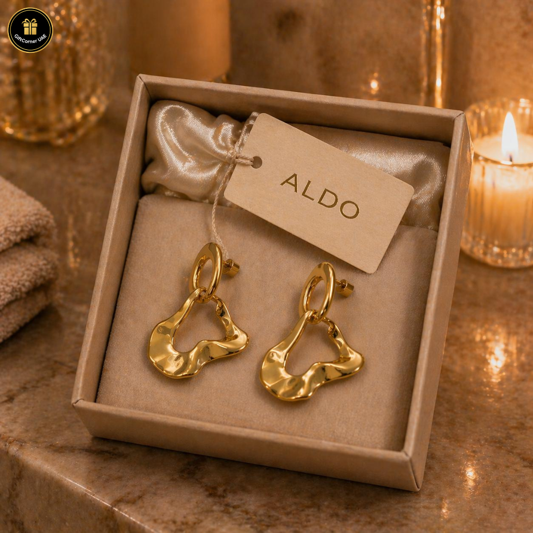 Gold earrings in a box with an Aldo tag on a warm-toned surface.