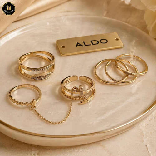 Set of gold rings on a ceramic dish with 'ALDO' branding.